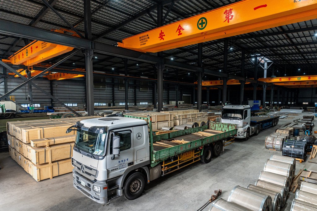 工廠內部兩輛卡車正在裝載金屬鋼材和鋼捲。