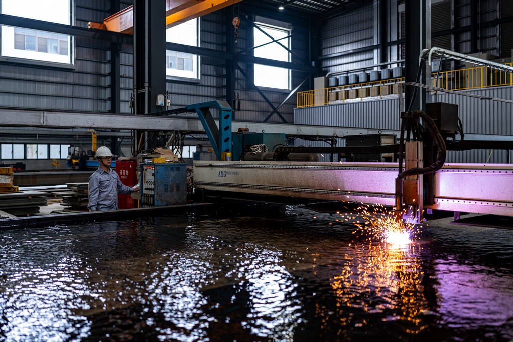 技術人員操作電漿水下切割機，水面反射火花。