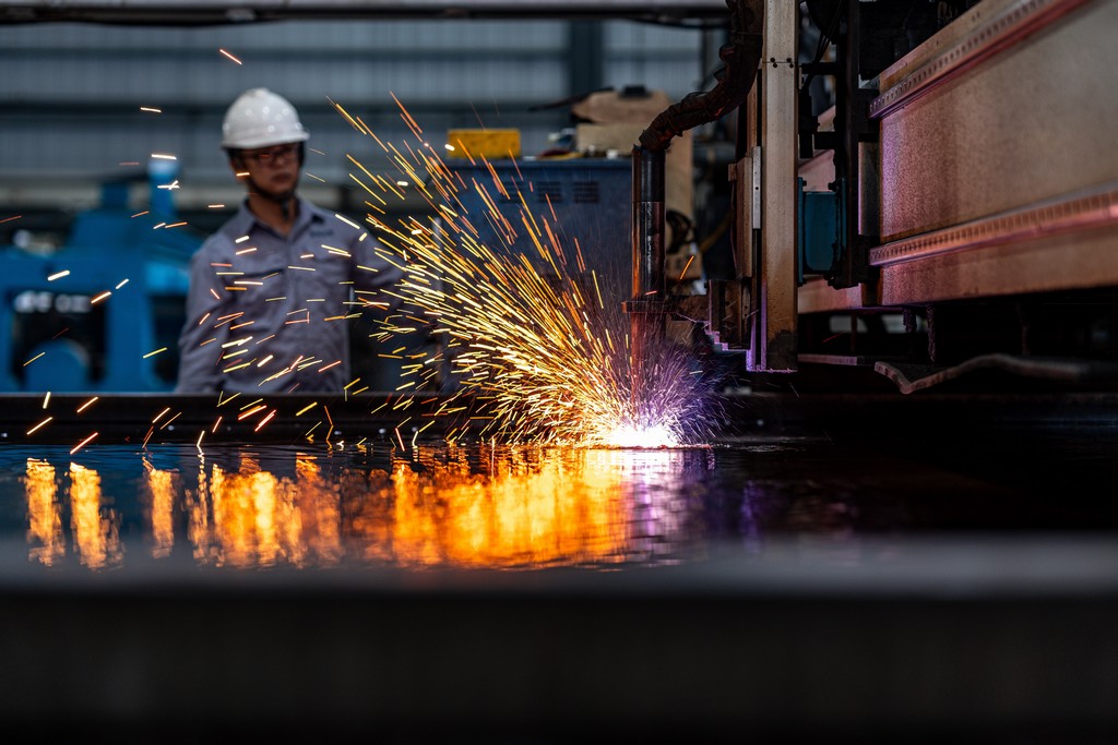 金屬雷射切割機作業，火花四濺，技術人員在後方。