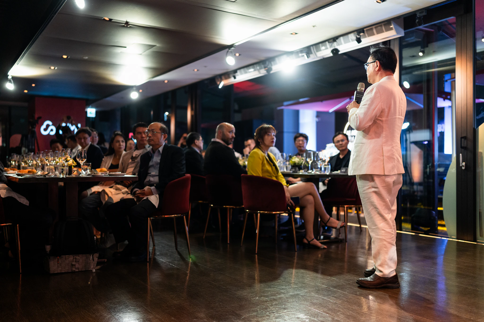 AI Alliance 領袖晚宴|講者與餐桌賓客 穿淺色西裝的講者在台北晚宴場地向坐在餐桌旁的賓客發言