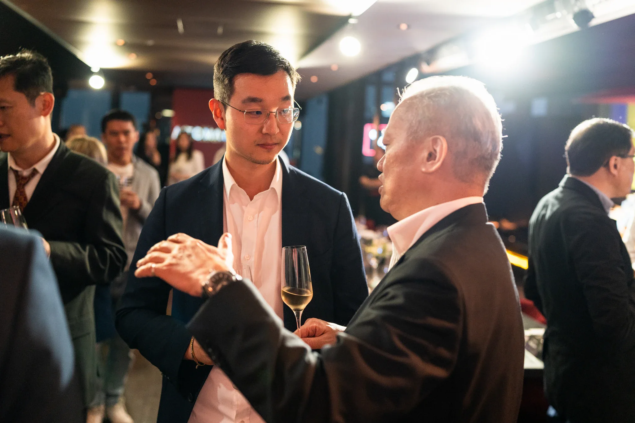 AI Alliance 企業交流活動|現場討論 兩位來賓在餐會交流時面對面討論,旁邊可見其他與會者