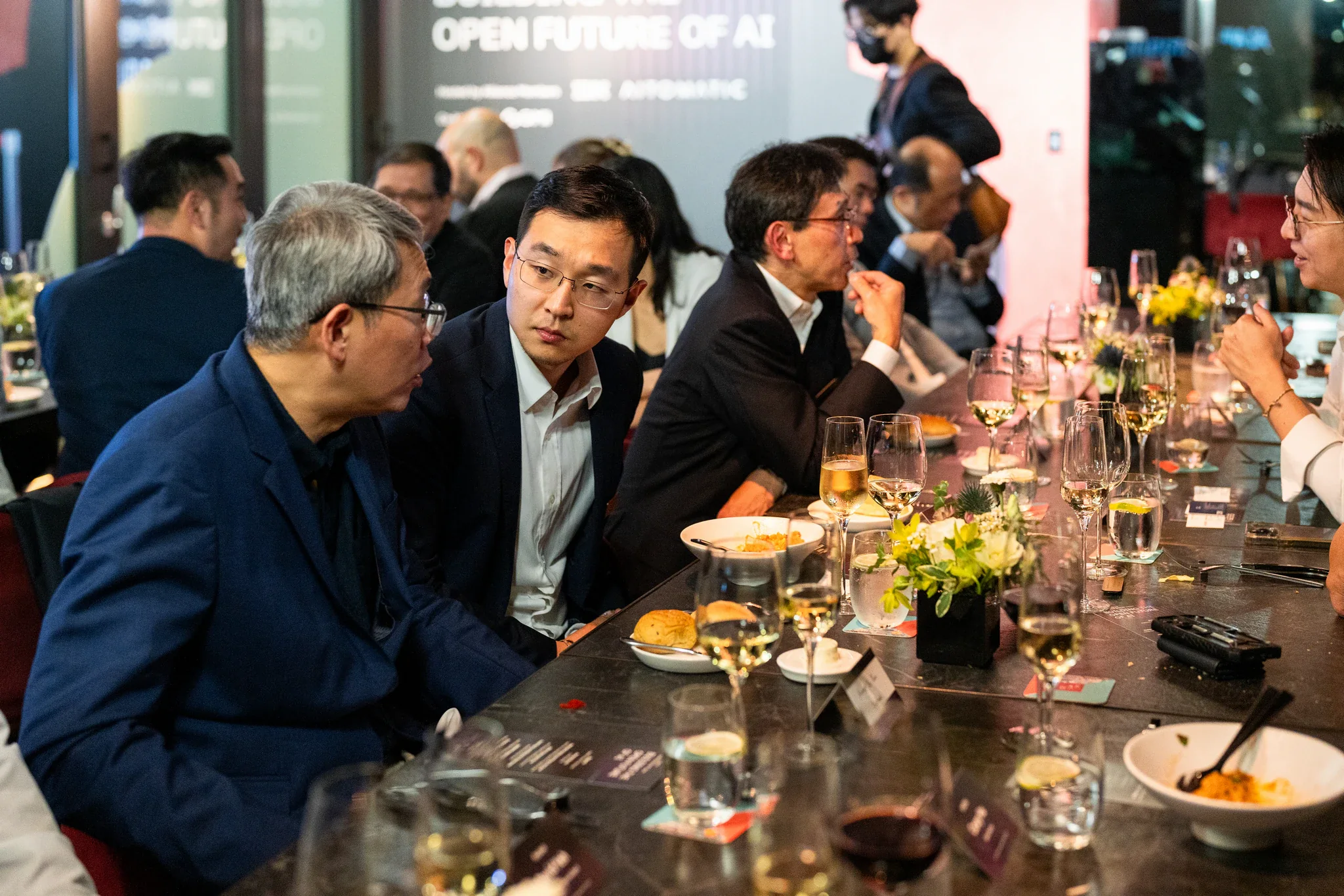AI Alliance 台北活動攝影|長桌晚宴 長桌兩側的來賓在晚宴中交談,桌上有花藝與餐點
