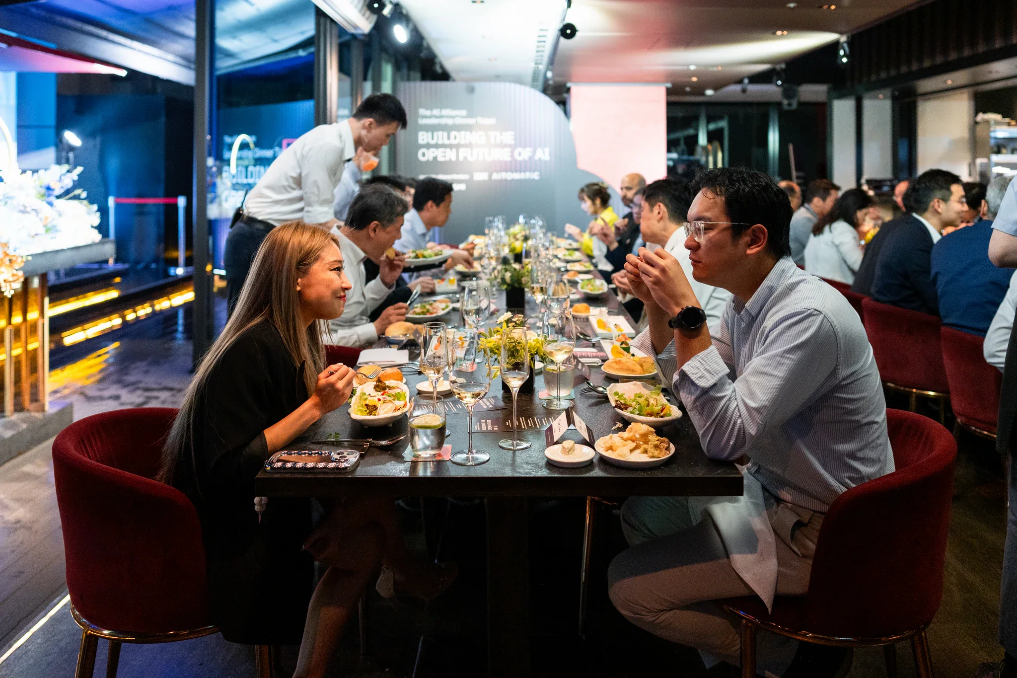 AI Alliance 晚宴攝影|餐桌交流全景 來賓圍坐長桌用餐,透過餐桌花藝可見整體交流氛圍