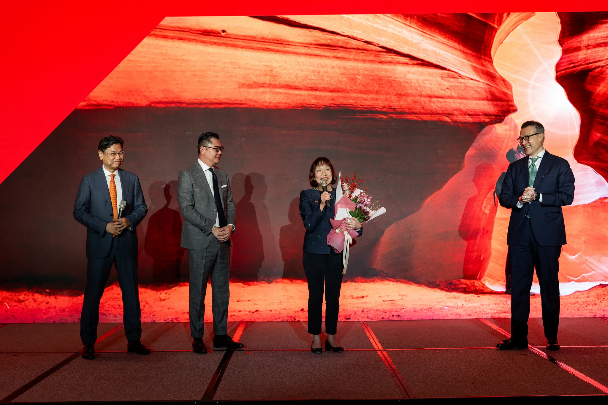 HSBC 2026 投資展望|舞台互動 數位參與者站在暖色投影畫面前,現場有花束與主持互動